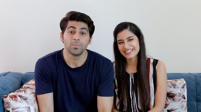 Attractive Indian couple happily talking to their friends over a video call/chat. Point of view shot of young boyfriend-girlfriend enjoying having a conversation with their relatives - lifestyle co...