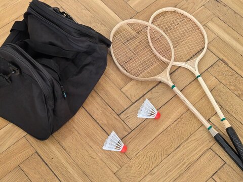 Badminton rackets shuttlecocks and sport bag on wooden parquet floor