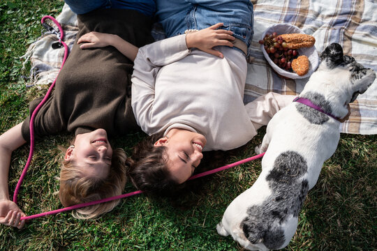 Couple relaxing on picnic blanket with dog in park