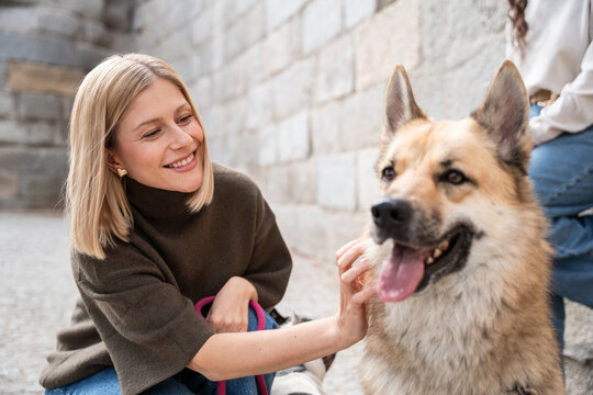 Woman petting dog on city street during relaxed walk