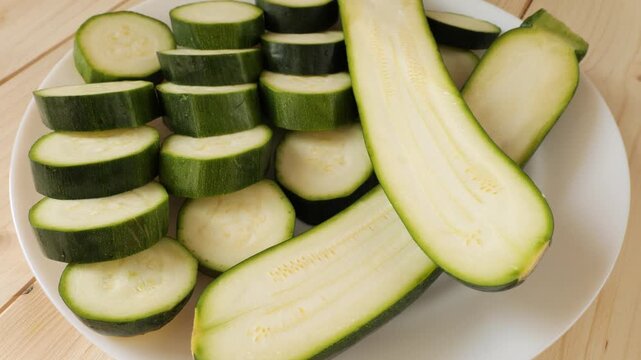 Fresh sliced green zucchini rotating on plate