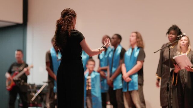 Woman choir conductor directing gospel singers on stage
