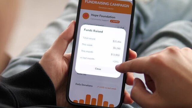 Modern crowdfunding UI demonstration. Person reviews fundraising statistics on a smartphone app. Showcases daily donation bars and revenue growth. Essential footage for charity promos, fintech ads