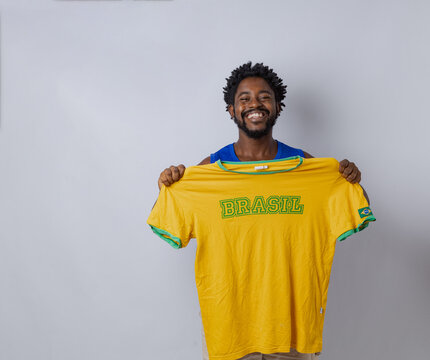 A Black Brazilian man celebrating in a photo studio wearing the Brazilian national team jersey for the World Cup. Rio de Janeiro, Brazil.