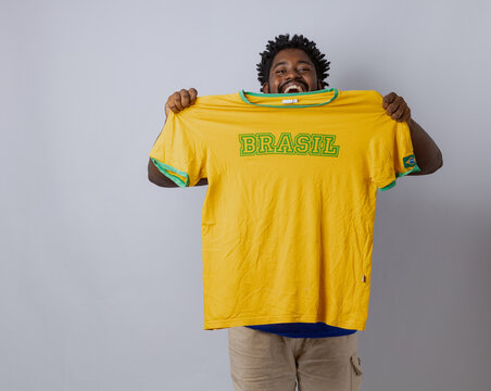 A Black Brazilian man celebrating in a photo studio wearing the Brazilian national team jersey for the World Cup. Rio de Janeiro, Brazil.