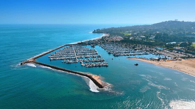 Large yacht club in Santa Barbara, California, USA. Drone footage near the shore of American Riviera on sunny day.