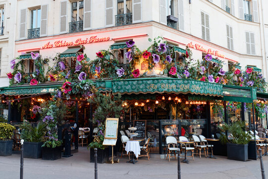 Paris, France-February 08, 2026 : Extravagant and enchanting facade of the historic Parisian brasserie "Au Chien Qui Fume," founded in 1740, lavishly decorated with cascading large purple and pink art
