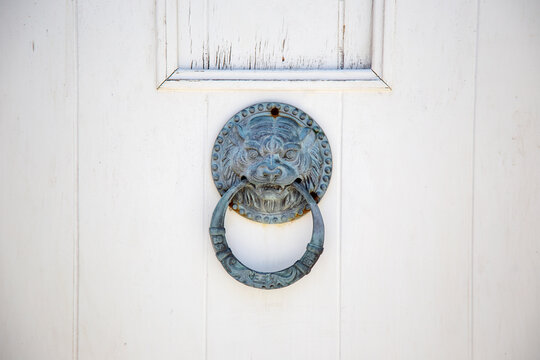 Antique lion head door knocker on white wooden door