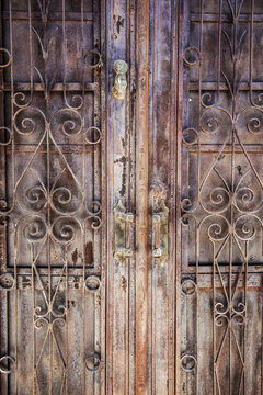 Weathered iron gate with rusty handles and scrollwork