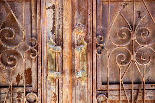Weathered iron gate with rusty handles and scrollwork