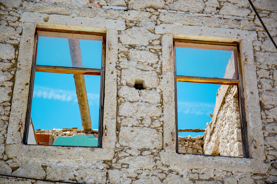 Abandoned stone house windows framing blue sky ruins