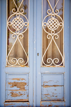 Weathered blue double door with ornate wrought iron grill