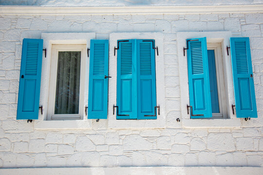 White stone wall with turquoise shutters and windows