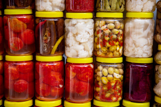 Assorted pickled vegetables in glass jars on market shelf