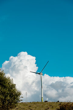 Wind turbine on spring grass under blue sky and cloud
