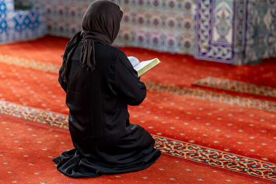 Muslim woman reading inside ornate mosque prayer hall