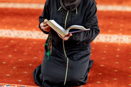 Muslim woman reading a book and praying inside a mosque