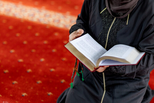 Muslim woman reading a book and praying inside a mosque