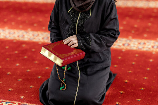 Muslim woman holding a book and prayer beads in mosque