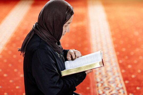 Muslim woman reading a book during prayer inside a mosque