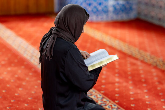 Muslim woman reading a book during prayer inside a mosque