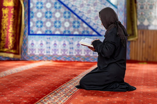 Muslim woman reading  while praying inside a mosque
