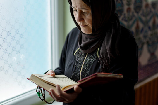 Muslim woman reading in mosque interior by window