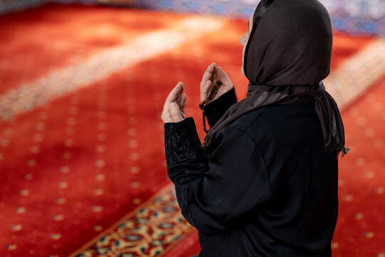 Muslim woman praying in mosque on red carpet interior