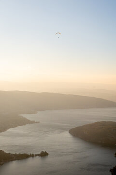 Sunset haze over Lake Annecy with lone paraglider