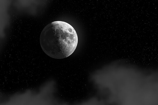 Moon against a starry sky with scattered clouds