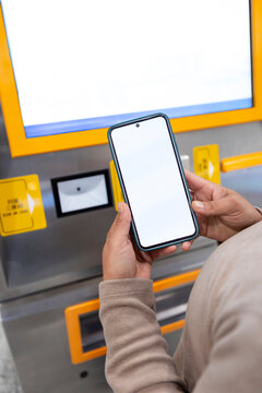Checking phone at a subway ticket machine