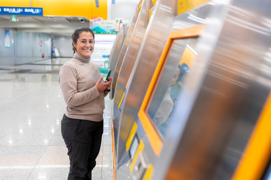 Smiling woman using a subway ticket machine