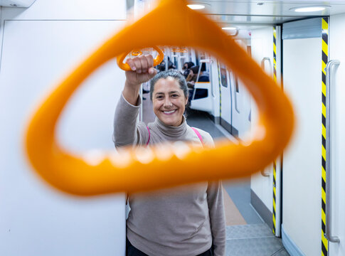 Woman smiling while holding subway handle