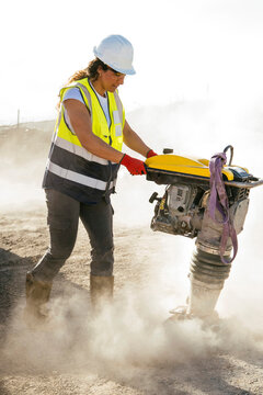 Construction worker operating rammer compactor on site