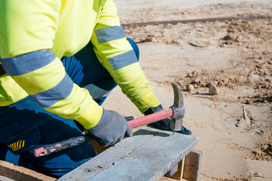 Construction worker using hammer on timber formwork site