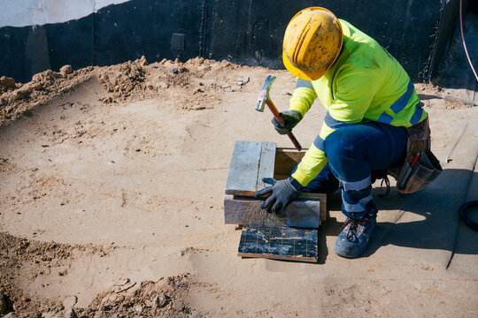 Construction worker hammering wood formwork on site