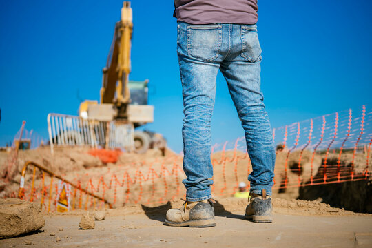 Worker at construction site with excavator in background