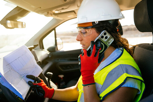 Woman construction worker on phone reviewing site plan