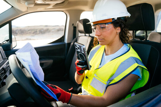 Female construction worker checking plans in work truck