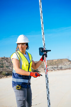 Female construction worker using survey staff on site