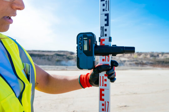 Surveying construction site with laser level and measuring rod