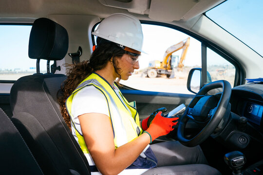 Female construction worker using smartphone in work truck