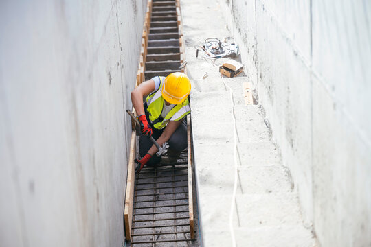 Female construction worker fixing rebar in trench site