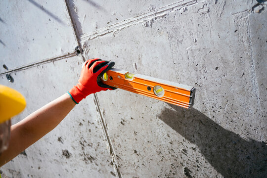Construction worker checking wall alignment with spirit level