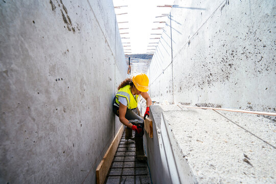 Female construction worker installing formwork in trench
