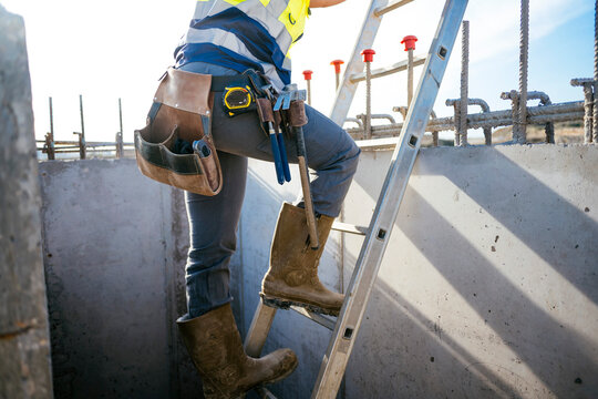 Construction worker climbing ladder at concrete site