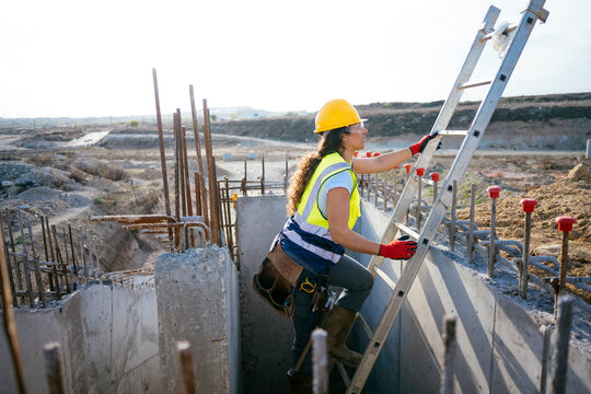Female construction worker climbing ladder at building site