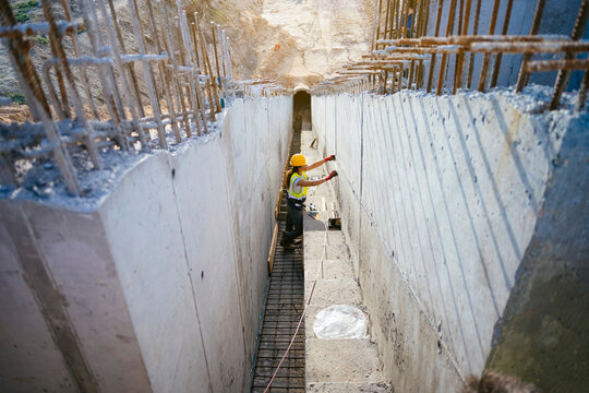 Female construction worker measuring concrete trench at site