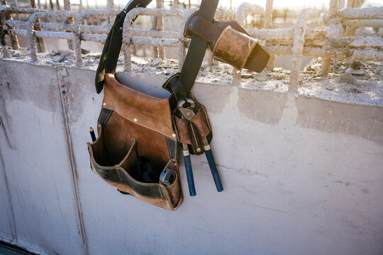 Construction worker tool belt and hammer on concrete wall