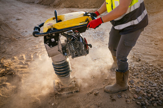 Female construction worker using rammer compactor on site